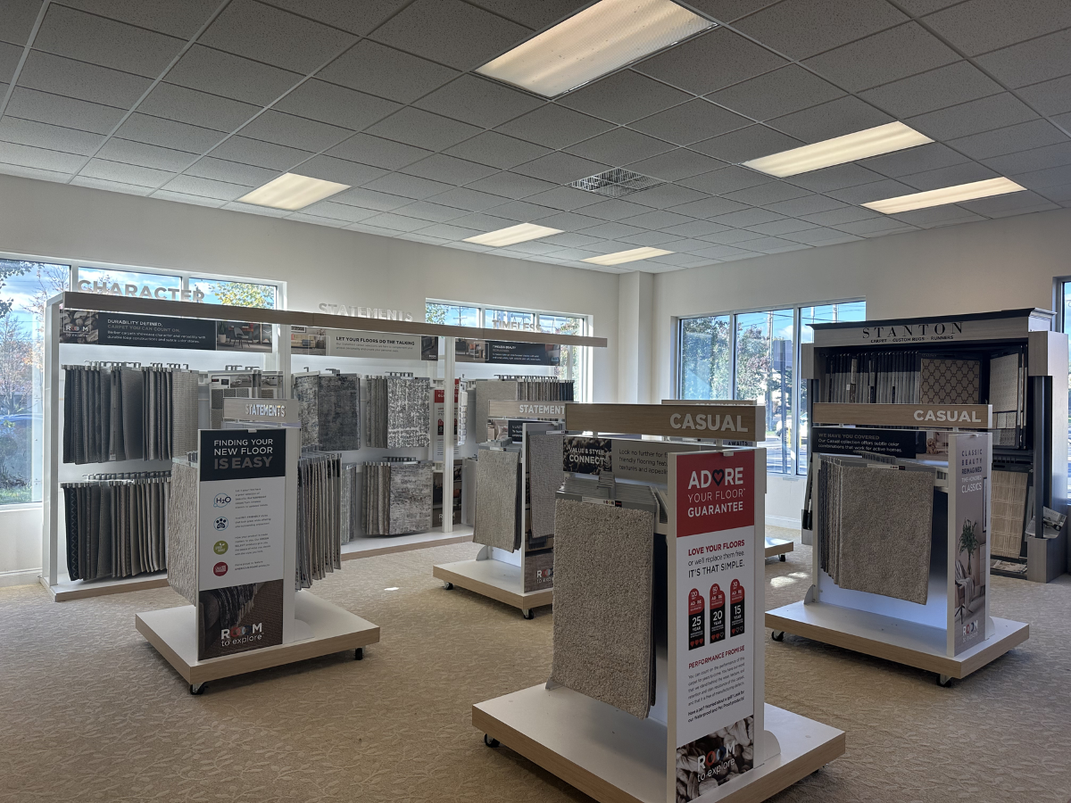 Carpet showroom with categorized displays, neutral samples, and customer-focused signage.