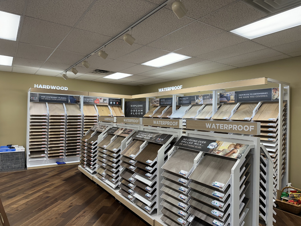 Flooring showroom featuring hardwood and waterproof sections with organized displays and banners.